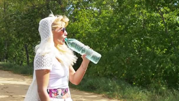 Krásná dívka s bílými vlasy sexy pije vodu z láhve. Zpomaleně. — Stock video