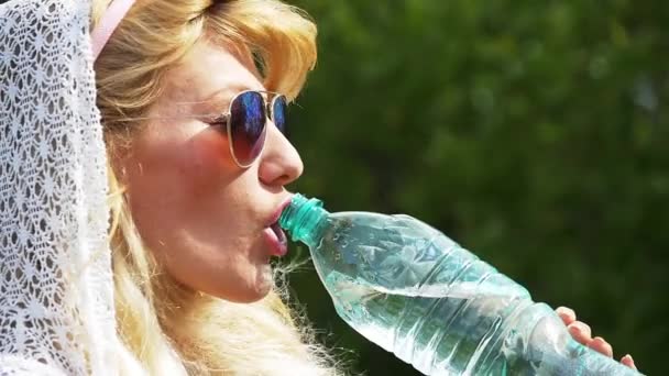 Hermosa chica con el pelo blanco sexy bebe agua de una botella. Movimiento lento . — Vídeos de Stock