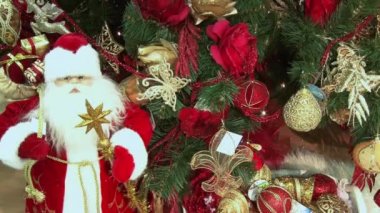 Ağacın altındaki karda komik oyuncak kardan adam. Parıldayan ışıklar arasında Noel ağacında Noel ve Yılbaşı oyuncakları.