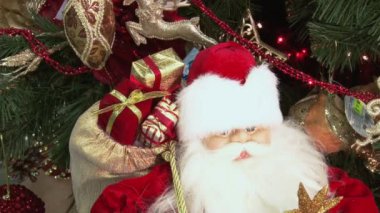 Ağacın altındaki karda komik oyuncak kardan adam. Parıldayan ışıklar arasında Noel ağacında Noel ve Yılbaşı oyuncakları.