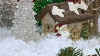 Ağacın altındaki karda komik oyuncak kardan adam. Parıldayan ışıklar arasında Noel ağacında Noel ve Yılbaşı oyuncakları.