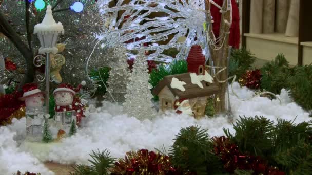 Boneco de neve de brinquedo engraçado na neve debaixo da árvore. Brinquedos de Natal e Ano Novo na árvore de Natal entre as luzes cintilantes . — Vídeo de Stock