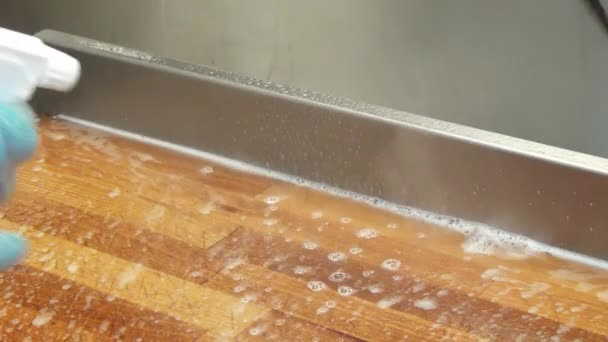 De toepassing van de reinigingsvloeistof op het oppervlak van een houten tafel. — Stockvideo