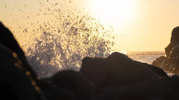 日落时海浪拍打岩石 在落日前向空中喷射水滴 — 图库照片