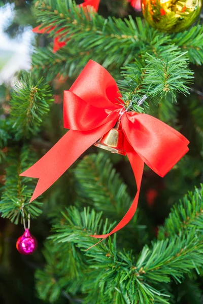 Kleine Glocke mit rotem Schleifenschmuck am Weihnachtsbaum — Stockfoto