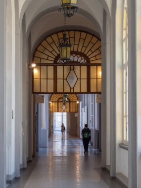 Geniş Pencereli Bir Hastanenin Uzun İç Koridoru ve Etrafta Yürüyen İnsanlar.