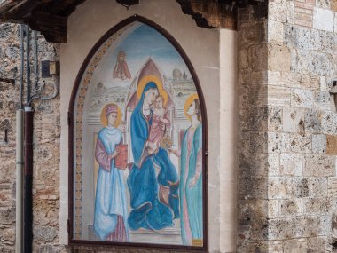 Ortaçağ Toskana 'nın San Gimignano şehrinde bulunan bir kamu binasının dış duvarında İsa' nın kollarında Meryem Ana 'yı tasvir eden dini resimler..