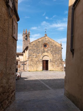 Monteriggioni, Siena 'daki Piazza Roma' da Çan Kulesi ve Santa Maria Assunta Kilisesi 'nin önündeki Dar Sokak manzarası.