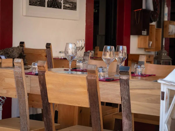 Empty Wooden Tables with Crystal Wine tasting Glasses Set for Outdoor Lunch in a Tuscan Village in Italy.