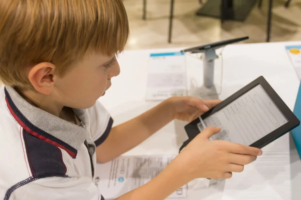 Kid (8-9 jaar) spelen met tablet pc in een winkel — Stockfoto