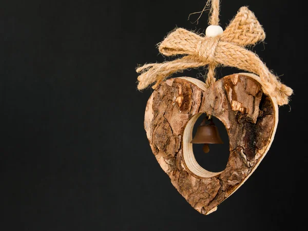 Bark wooden heart on a rope with little opaque brass bell in the — Stock Photo, Image
