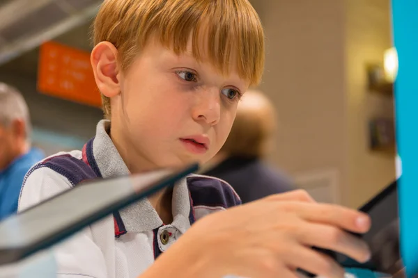 Kid (7-8 jaar) speelt met de tablet pc in een winkel — Stockfoto