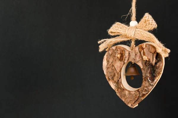 Corazón de madera de corteza en una cuerda con pequeña campana de latón opaco en el —  Fotos de Stock