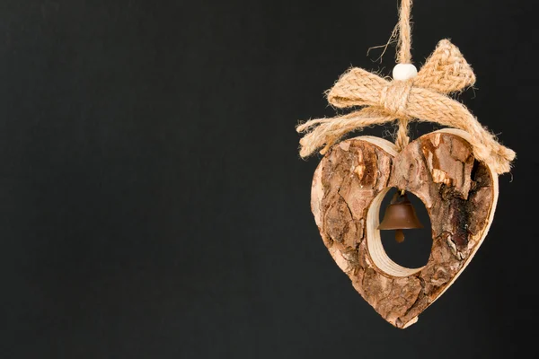 Bark wooden heart on a rope with little opaque brass bell in the — Stock Photo, Image