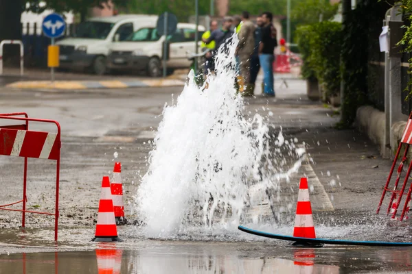 Vodu spurtu silnice vedle dopravní kužely — Stock fotografie