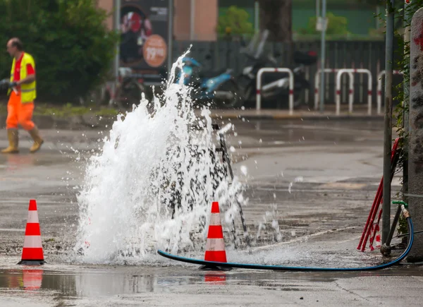 Vodu spurtu silnice vedle dopravní kužely — Stock fotografie