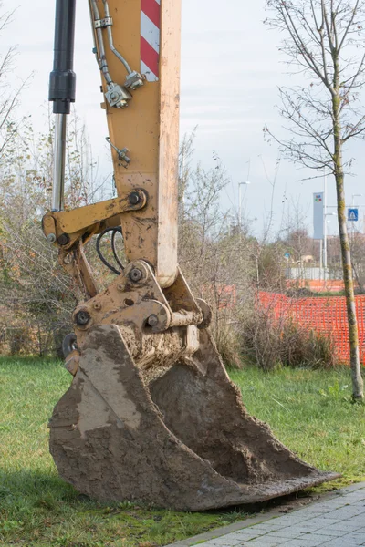 Närbild av leriga grävmaskin spade på gräs nära konstruktion är — Stockfoto