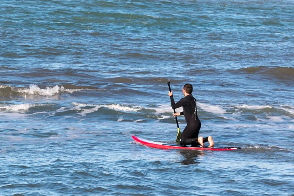 Mann paddelt auf rotem Brett, Surfer — Stockfoto
