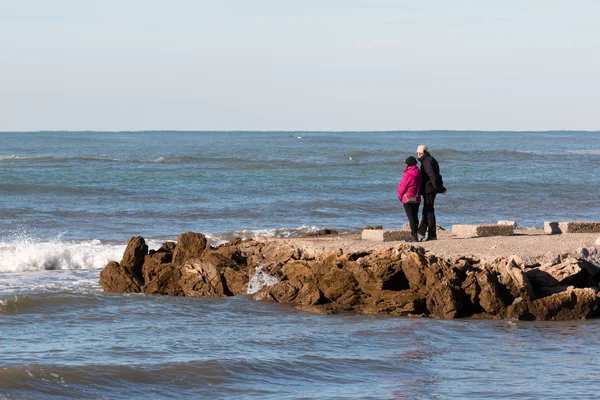Starší pár si pohled na mořského pobřeží v zimě — Stock fotografie