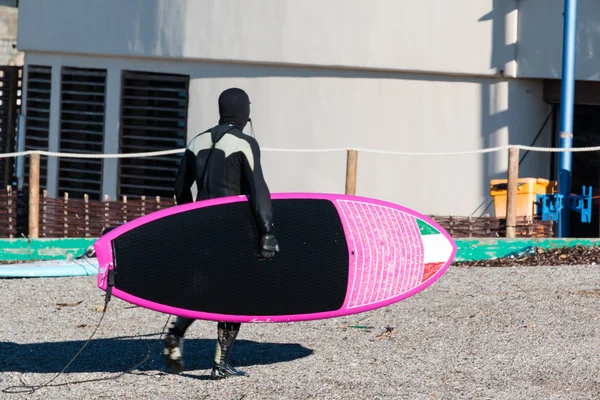 Surfer zwarte wetsuit met roze bord in de winter — Stockfoto