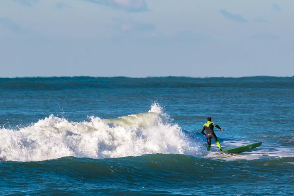 Surfista preto e verde wetsuit equitação a onda — Fotografia de Stock