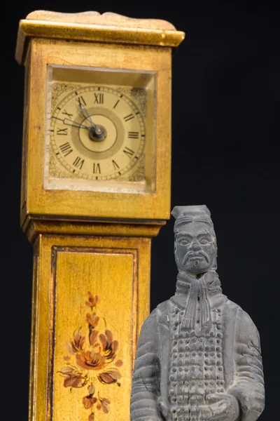 Gray oriental man statuette, retro alarm clock tower in backgrou — Stock Photo, Image