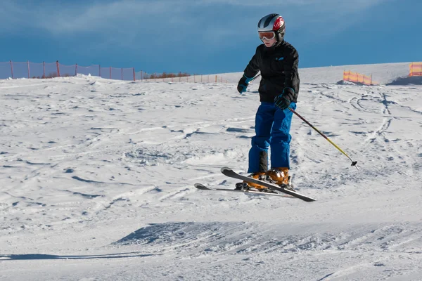 Pouco esquiador executa salto na neve — Fotografia de Stock