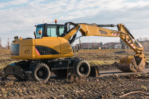 Excavadora amarilla con pala fangosa en el sitio de construcción — Foto de Stock