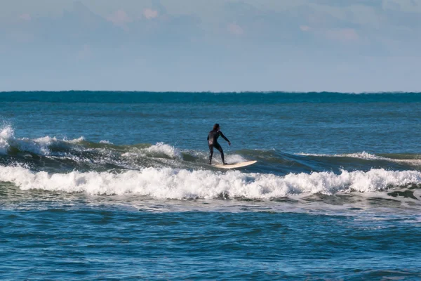 Surfista terno preto cavalgando a onda — Fotografia de Stock