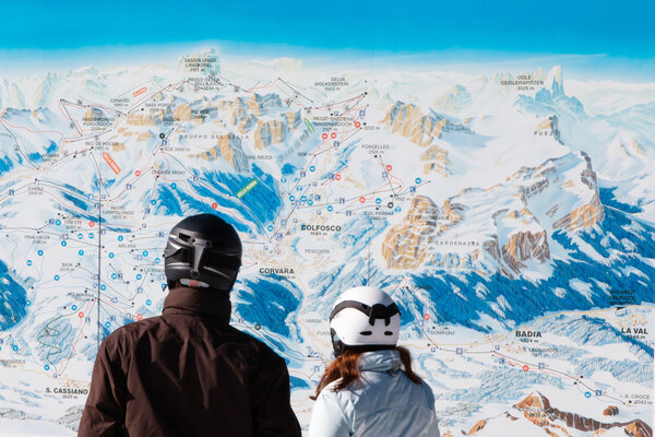 skiers with safety helmets in front of ski map