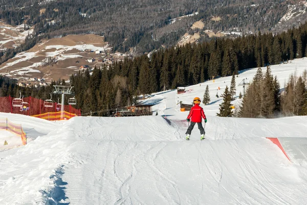 Petit skieur avec casque en pente de ski ensoleillée — Photo