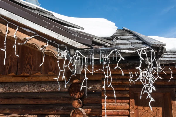 Chalet close-up: gutter with ice and turned off christmas lights — Stock Photo, Image