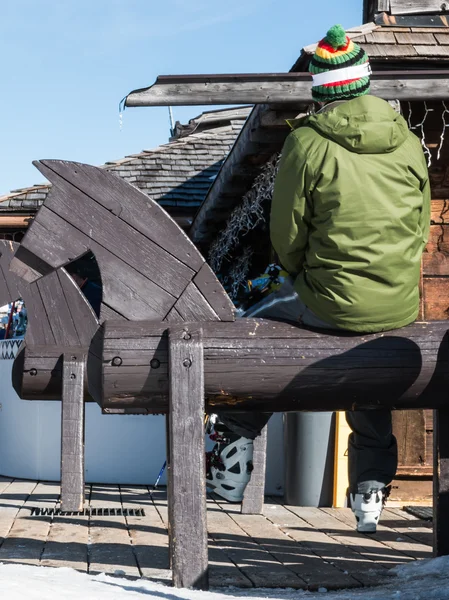 Skieur avec des chaussures de ski relaxant sur banc en bois en forme de cheval — Photo