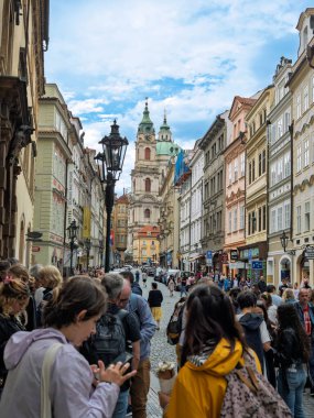 Mala Caddesi 'ndeki kalabalık St. Nicholas Kilisesi' ne doğru ilerliyor Bulutlu Mavi Gök, Prag, Çek Cumhuriyeti.