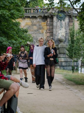 Alternatif tarzı olan bir grup genç parkta eski taş kemer yoluna doğru yürüyor..