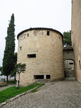 Büyük yuvarlak taş kule Büyük selvi ağacı ve kale binaları, Brescia, İtalya.