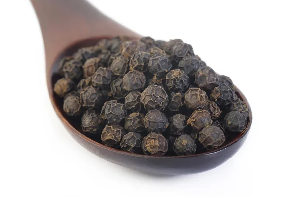 Zwarte peper zaden in houten lepel — Stockfoto