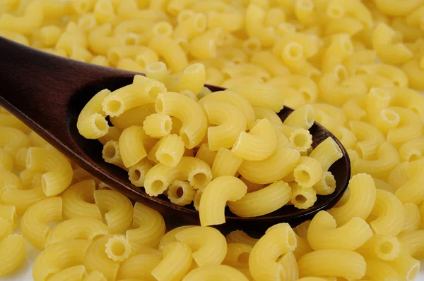 Raw pasta macaroni in wooden spoon — Stock Photo, Image