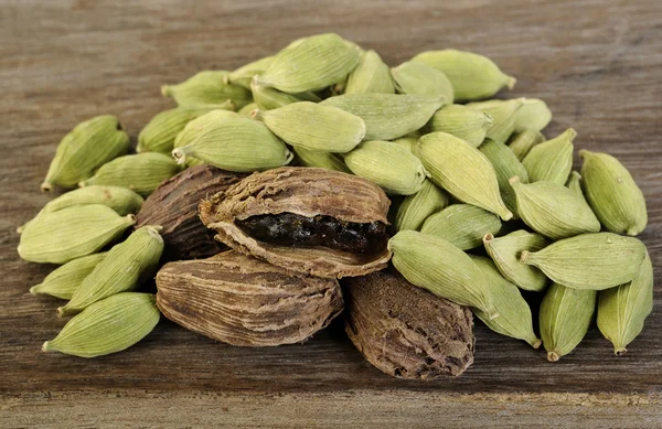 Cardamomo negro y verde sobre fondo de madera —  Fotos de Stock