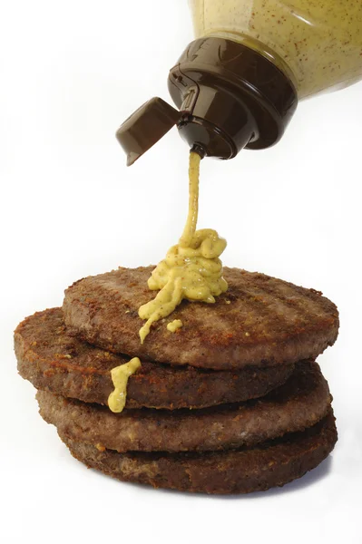 Senapssås faller från flaska på burger kotlett kött malet kött — Stockfoto