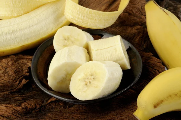 Sliced banana in bowl on wooden background — Stock Photo, Image