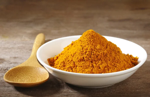 Cúrcuma en polvo en plato blanco sobre fondo de madera — Foto de Stock