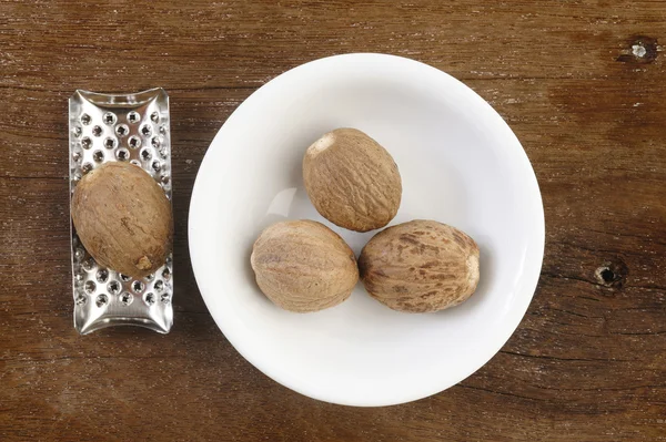 Nuez moscada y rallador sobre fondo de mesa de madera — Foto de Stock