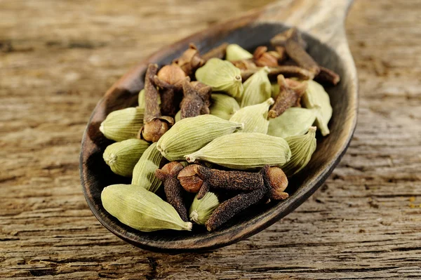 Cardamomo seco com cravo seco em colher de madeira velha — Fotografia de Stock