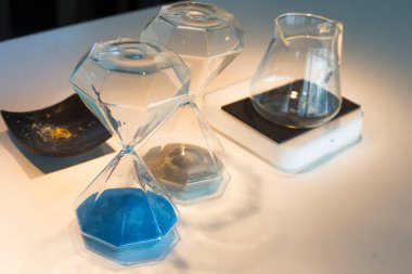 Mavi bir kum saatinin ampulleri arasından geçen zamanı ölçen kum.