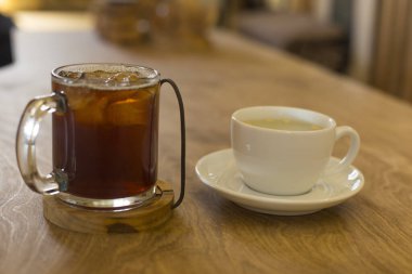 Buzlu kahve ve ahşap masada sıcak çay.