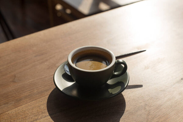 cup of espresso with shadow on wooden table