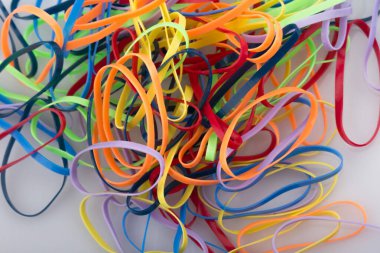 Beyaz arkaplanda renkli lastik bantlar yığını.