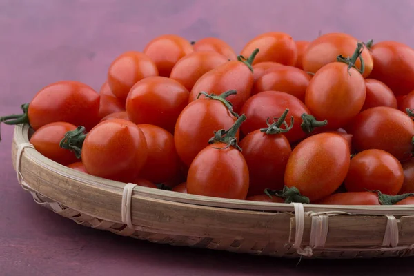 Tomates cereja em uma cesta isolada em rosa. — Fotografia de Stock