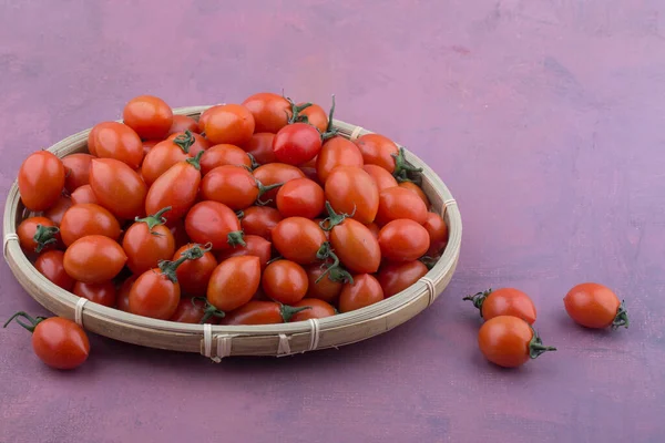 Tomates cereja em uma cesta isolada em rosa. — Fotografia de Stock